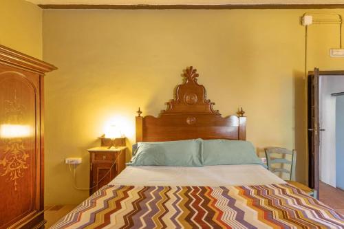 a bedroom with a large bed with a wooden headboard at Can Marc in Dosríus