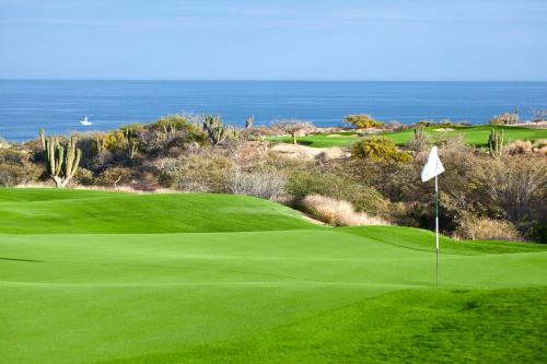 a green golf course with the ocean in the background at Casa Sonrisa by Cabo Villas in San José del Cabo