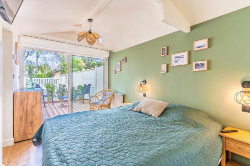 une chambre avec un lit bleu et un balcon dans l'établissement Villa Fleurs des Pins, piscine chauffée , 80 m de la plage Pereire, à Arcachon