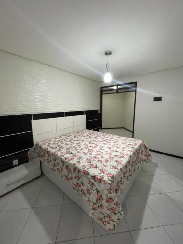 a bedroom with a bed with a flowered blanket at Casa Alto Padrão para o São João in Campina Grande