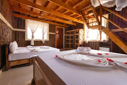 a room with two beds in a room with wooden ceilings at Diacarisma Boutique Resort Nungwi in Nungwi