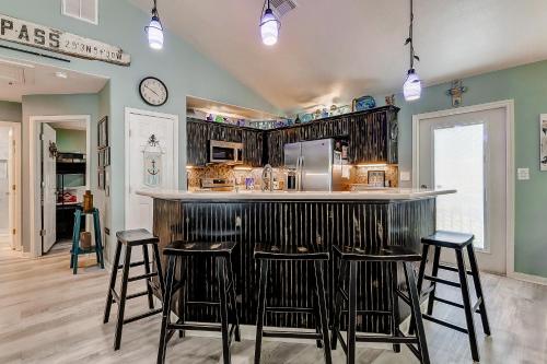 a kitchen with a bar with stools around it at Blue Heaven by Bolivar Escapes in Crystal Beach