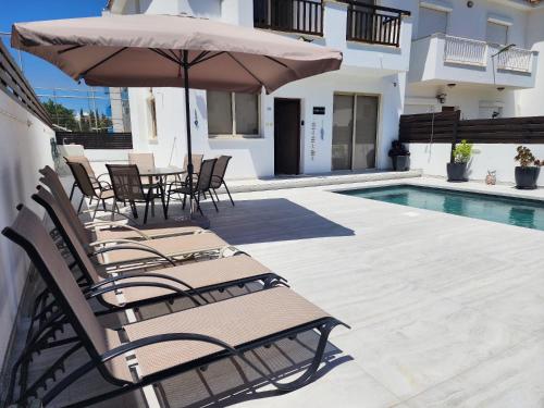 a group of chairs and an umbrella next to a pool at Yama's Villa - Polyxenia luxury, protaras, cyprus in Protaras