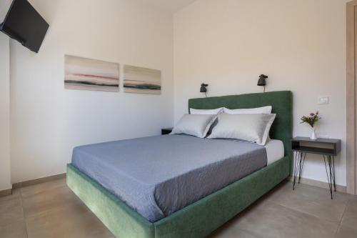 a bedroom with a bed with a green headboard at Cozy Light Nest Chania Crete in Kounoupidhianá
