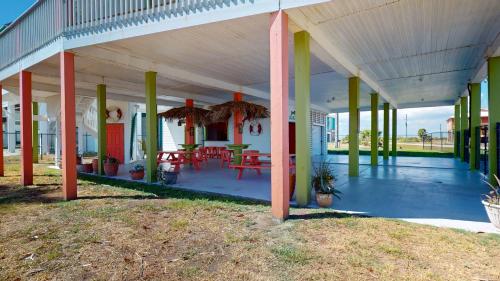 a covered porch with tables and chairs on it at Casa Bella by Bolivar Escapes in Crystal Beach
