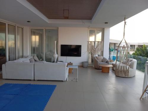 a living room with white furniture and a flat screen tv at SEASHELL Luxury Chalet in Sīdī ‘Abd ar Raḩmān