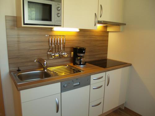 una pequeña cocina con fregadero y microondas en alpinea Appartements, en Ischgl