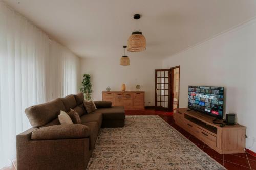 a living room with a couch and a flat screen tv at Best Houses 53 - The Daisy Moon House in Serra de El-Rei