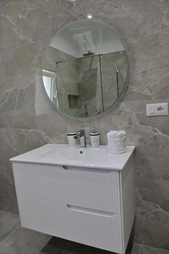 a bathroom with a white sink and a mirror at Ferienhaus Qelia in Durrës