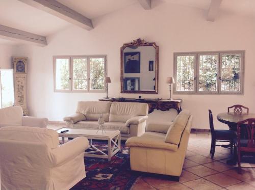 Elle comprend un salon doté d'un mobilier blanc et d'un miroir. dans l'établissement La GUIRAMANDE, à Aix-en-Provence