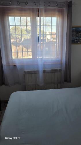 a bedroom with a bed and two windows with white curtains at La Dimora Di Ale in Monterosi