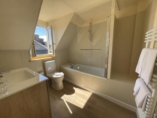 a bathroom with a tub and a toilet and a sink at Le Trouville - Hôtel de Charme in Trouville-sur-Mer
