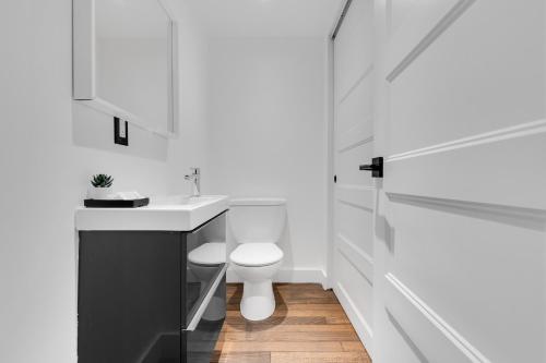 a white bathroom with a toilet and a sink at The SFX Old Port in Montréal