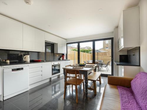 a kitchen with white cabinets and a table and chairs at Stylish 5BR Home in the Heart of Spitalfields Walk to Brick Lane & Shoreditch in London