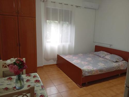 a bedroom with a bed and a table with a vase of flowers at Arta room in Durrës