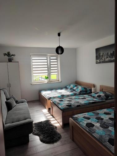 a bedroom with two beds and a chair and a window at Apartamenty NOVA - BLISKO ENERGYLANDII in Zator