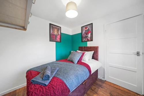 a bedroom with a bed with a red and blue blanket at Beautiful 4 Bedroom Home with Parking in Rugby in Clifton upon Dunsmore