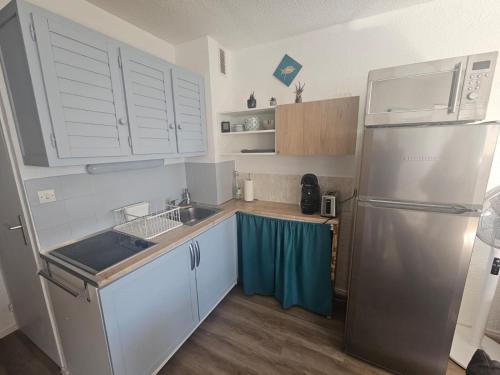 une cuisine avec des armoires blanches et un réfrigérateur en acier inoxydable dans l'établissement Le Cocon de Julie, au Barcarès