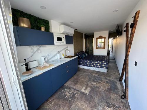 a kitchen with blue cabinets and a couch in the background at LA SUITE DES CHARMES - village naturiste - coursives - port nature 2 in Cap d'Agde