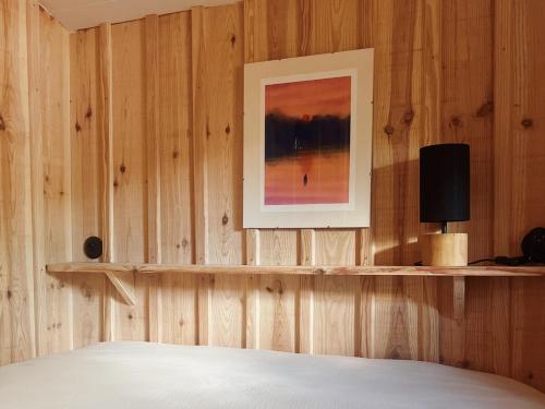 une chambre avec un mur en bois avec un tableau et un lit dans l'établissement Cabin, terrace and enclosed garden, à Lanton