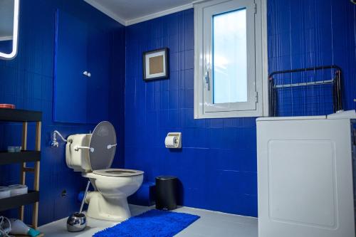 a blue bathroom with a toilet and a window at Acropolis 360 Residence,2 bedr in Athens
