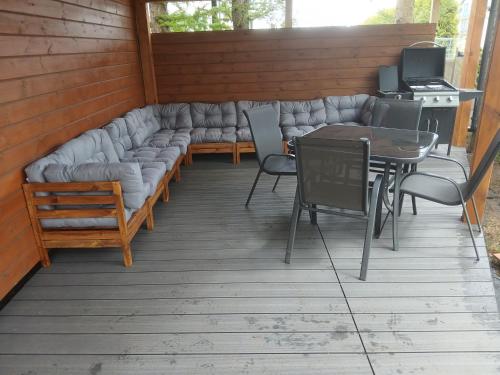 a covered patio with a couch and a table and chairs at Wakacyjny dom in Karwia