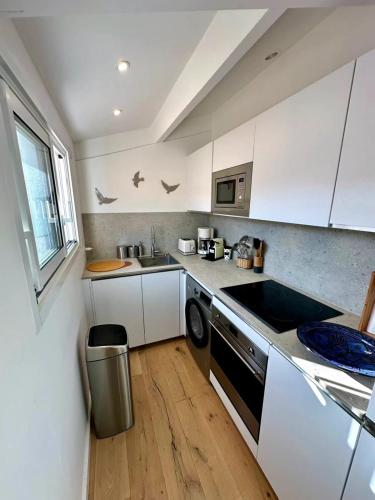 une cuisine blanche avec un évier et un lave-vaisselle dans l'établissement The Lighthouse Quiet terrace apartment on the port, à Saint-Martin-de-Ré