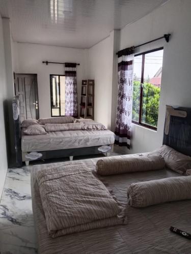 a bedroom with two beds and a couch and a window at LA97 Homestay in Berastagi