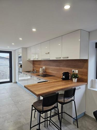 une cuisine avec des armoires blanches et un comptoir en bois dans l'établissement House La Belle Escapade, à Sainte-Croix-en-Plaine