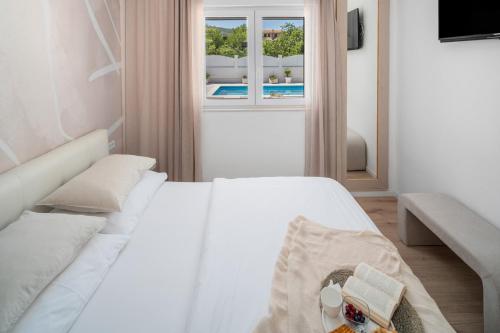 un letto bianco in una stanza con una finestra di VILLA TUGARKA private pool, fitness, play-house, great for families, max 6 per. a Tugare