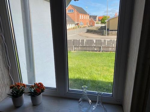 a window with two wine glasses and flowers on a window sill at Dejlig gårdhave 5 soveværelser in Harboør