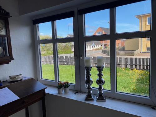 a room with a window with three candles on a counter at Dejlig gårdhave 5 soveværelser in Harboør