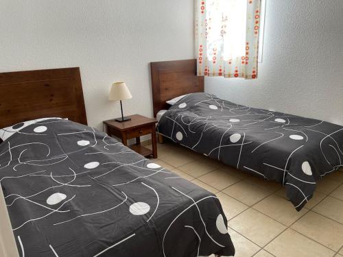 a bedroom with two beds and a lamp and a bed sidx sidx sidx at Appartement 2 chambres in Prayssac