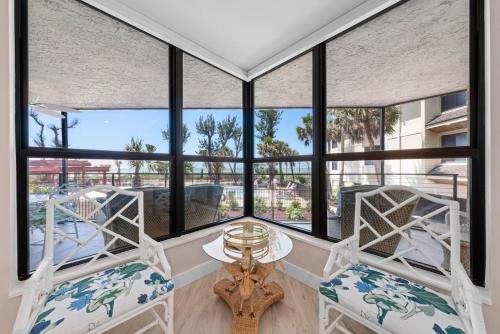 a room with windows and a table and chairs at Pine Cove 104 in Sanibel