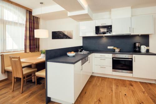 a kitchen with white cabinets and a dining table at Bischoferhaus in Serfaus