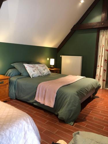 a bedroom with a large bed with green walls at Chez MASK Brocante in Yvetot Bocage
