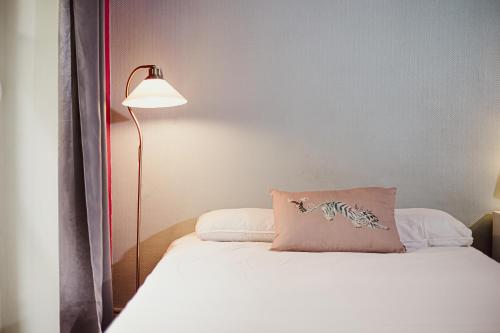 a bedroom with a bed with a pillow and a lamp at Residence Avy Baudelaire - Lyon Bellecour in Lyon