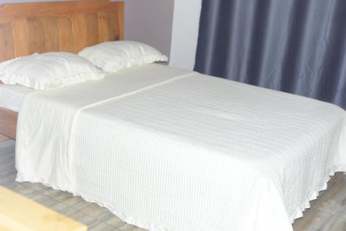 a bed with a white blanket on top of it at Mountain Huye Peak View Haus in Butare