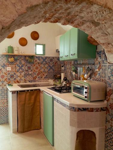 una cucina con armadi verdi e forno a microonde di Casa Antica Cibbun a Martina Franca