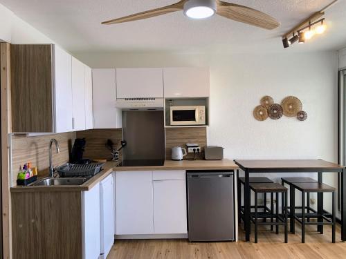 une cuisine avec des armoires blanches et une table avec des chaises dans l'établissement T2 les pieds dans le sable !, à Canet