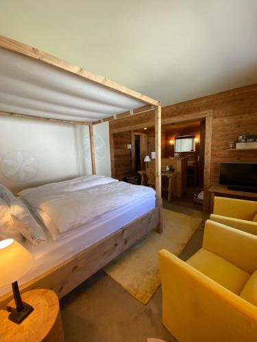 a bedroom with a bed and a couch and a television at Maiensässhotel Guarda Val in Lenzerheide