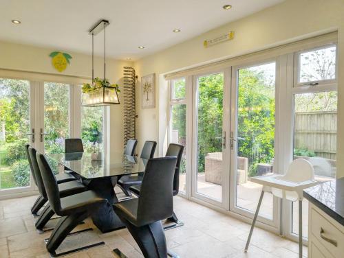 a dining room with a glass table and black chairs at Blacksmiths Cottage, Bosham in Bosham
