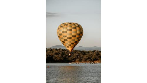 a hot air balloon flying over a body of water at Edgar at Lake George Winery at Tiny Away in Collector