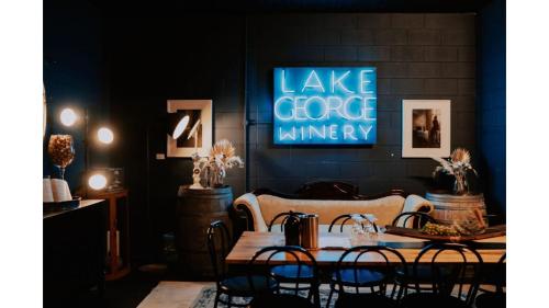 a table with chairs and a blue sign on a wall at Edgar at Lake George Winery at Tiny Away in Collector