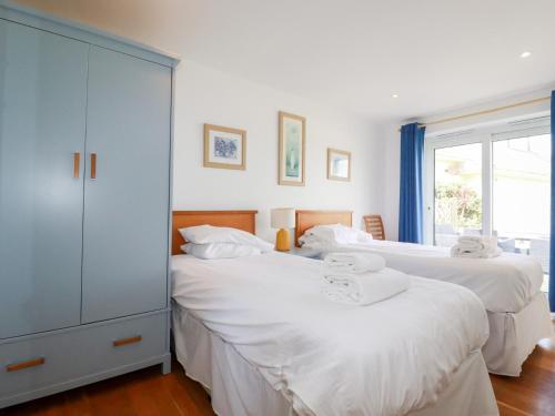 two white beds in a room with a window at The Beach House in Newquay