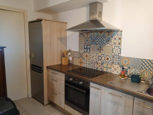 Il comprend une cuisine équipée d'une cuisinière. - un four supérieur à côté d'un réfrigérateur dans l'établissement Gîte sur un domaine viticole en agriculture biologique, à Cessenon