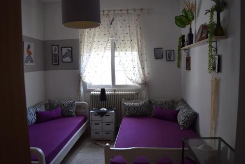 a living room with purple beds and a window at Dimitris house in Paralía Avdhíron