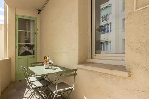 une table et des chaises sur un balcon avec une fenêtre dans l'établissement Elégant et moderne T4 à 100M de La Croisette, à Cannes
