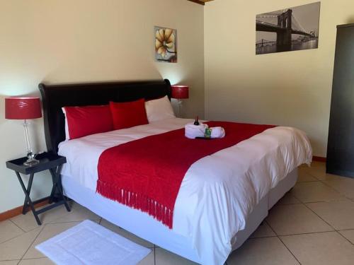 a bedroom with a large bed with a red blanket at Catwalk Lodge in Pretoria