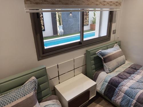 a small room with two beds and a window at Luxurious Stella 2-bedroom Apartment with Pool in Hammamet Nord